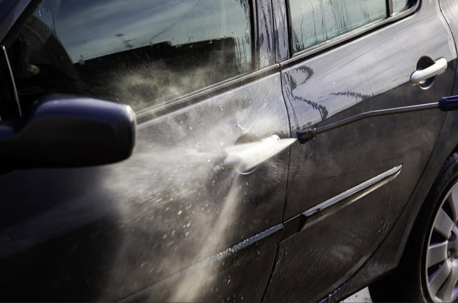 Water spraying against a car door under strong Gulf sunlight, showing the harsh UAE summer conditions tint has to withstand